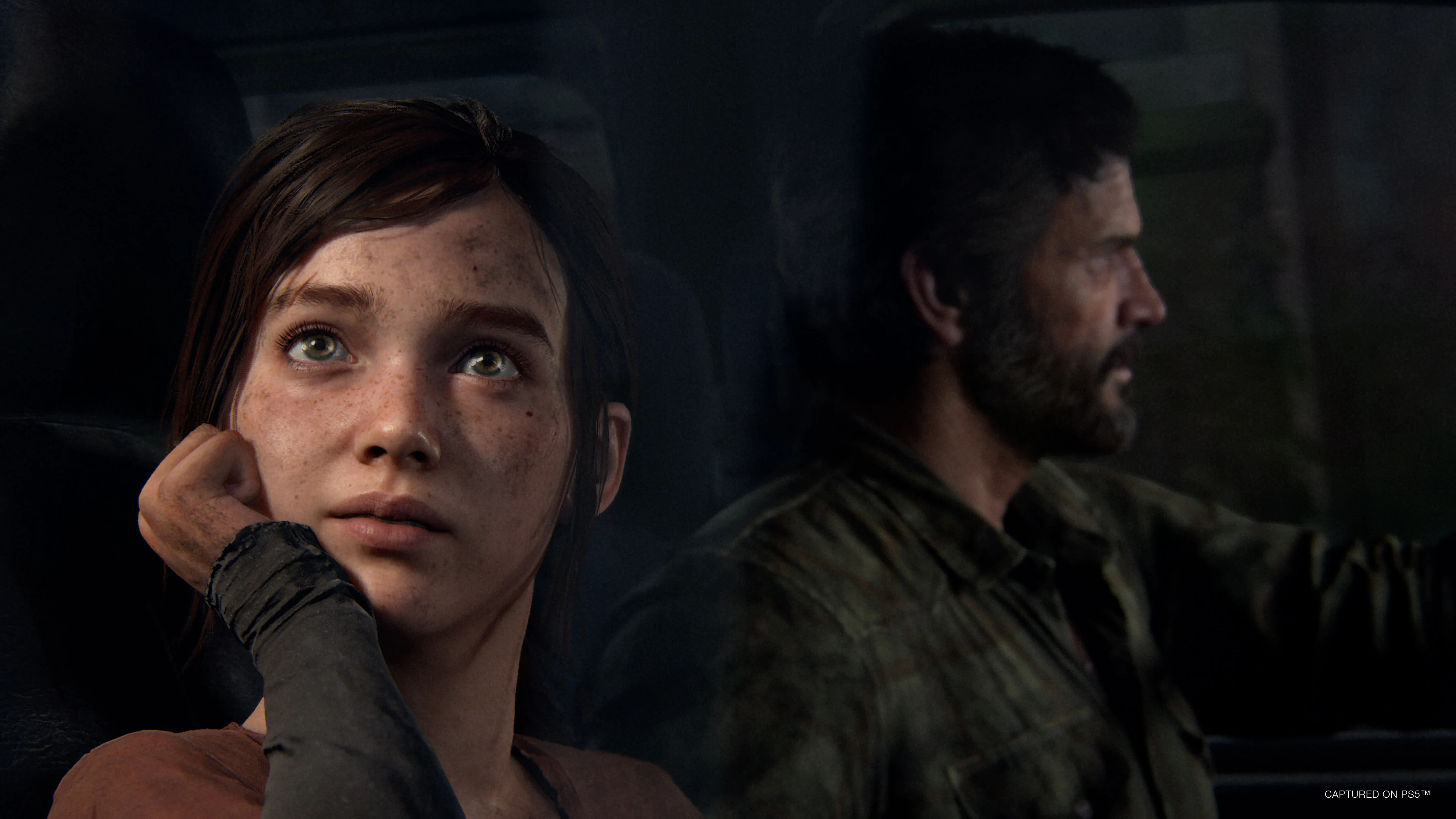 The Last of Us (Naughty Dog) Ellie looks out the truck window while Joel drives; both are covered in the grime of surviving a post-apocalyptic world