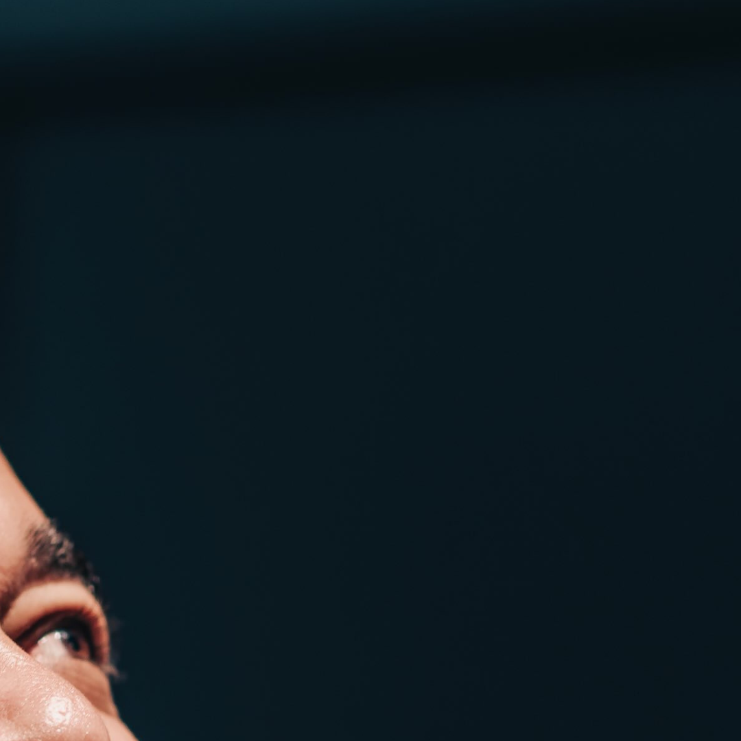 A very close up shot of Velvet's left eye, eyebrow and nose, against a dark bluey-green (#0A1920) background. Arts Court Atelier c: Curtis Perry Photography